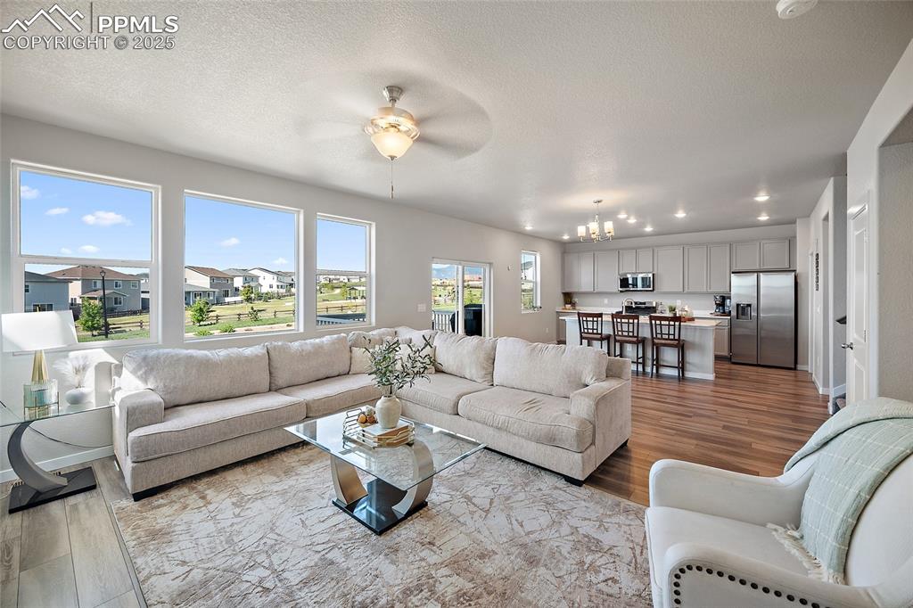 Image 3 of 41: Living room with a chandelier, wood finished floors, ceiling fan, recessed