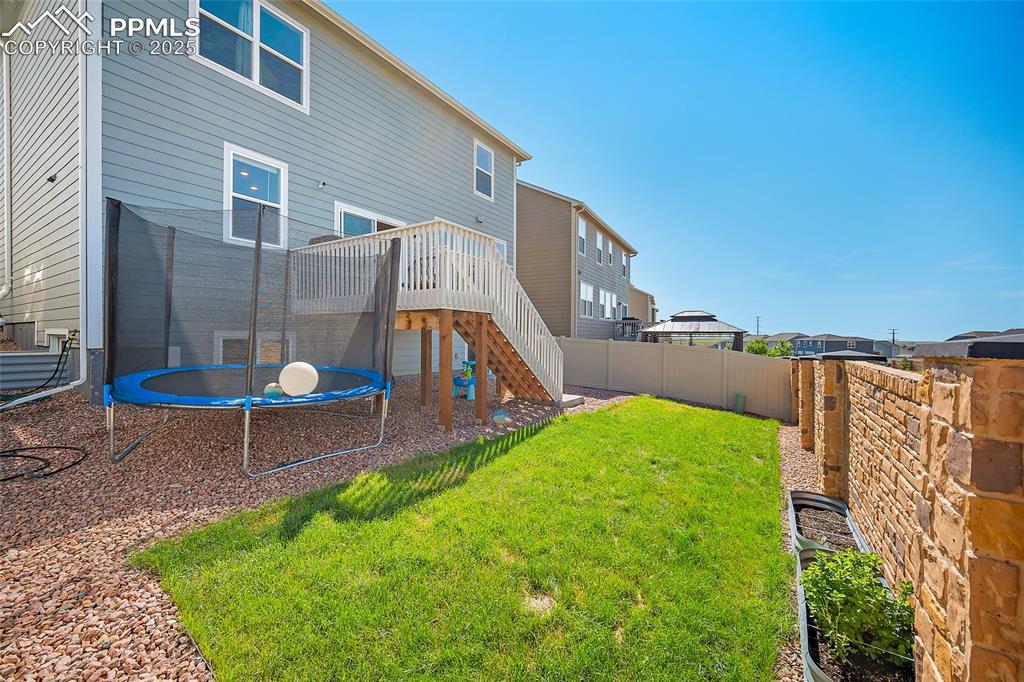 Image 31 of 41: Rear view of property with a trampoline, a fenced backyard, stairway, and a