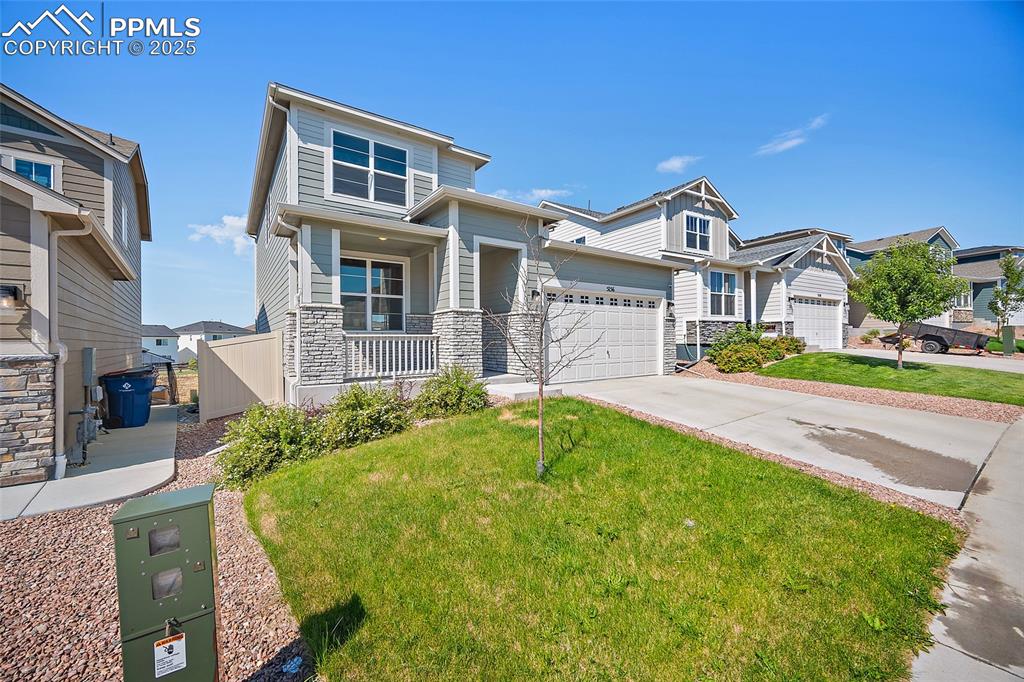 Image 41 of 41: View of front of home with a porch, driveway, stone siding, a front lawn, a
