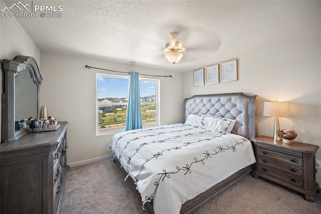 Image 7 of 41: Carpeted bedroom with a textured ceiling and ceiling fan