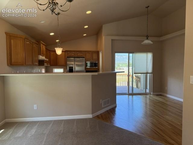 Image 9 of 24: Open-concept kitchen and dining area featuring vaulted ceilings, recessed l
