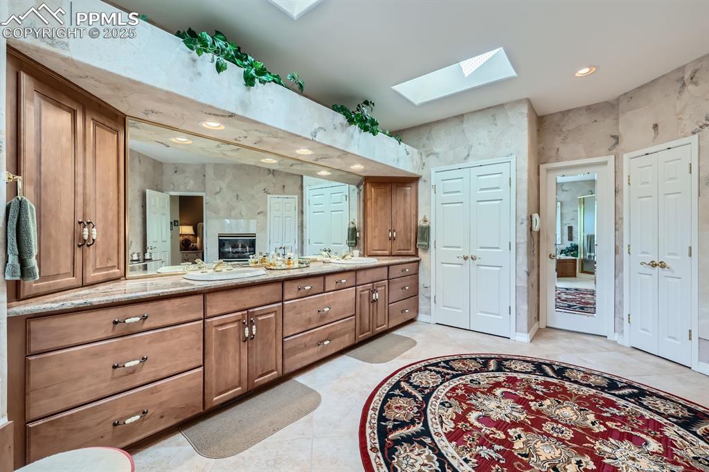 Image 15 of 49: Large primary spa like bathroom with skylights and dual vanity two linen cl