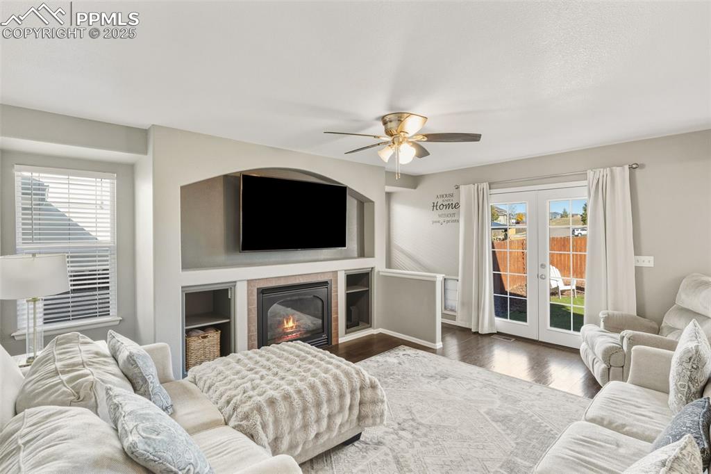 Image 18 of 34: Living area with wood finished floors, a tile fireplace, french doors, and