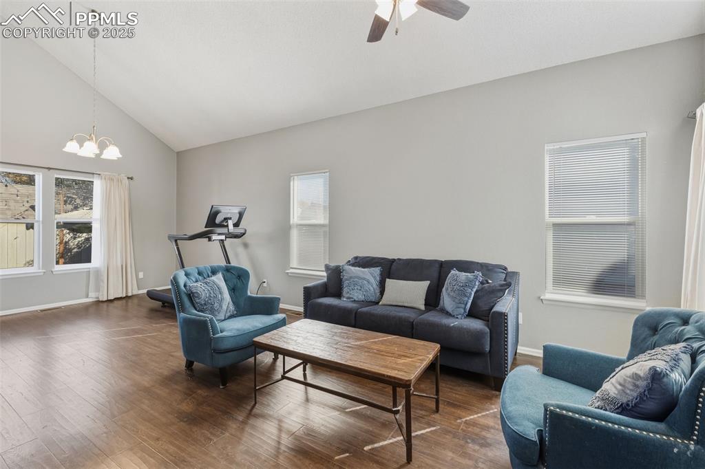 Image 21 of 34: Living area featuring wood finished floors, high vaulted ceiling, a chandel