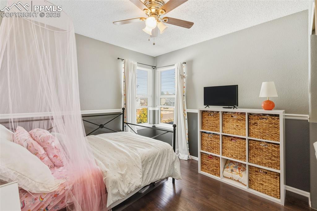 Image 27 of 34: Bedroom featuring wood finished floors, a textured ceiling, and a ceiling f