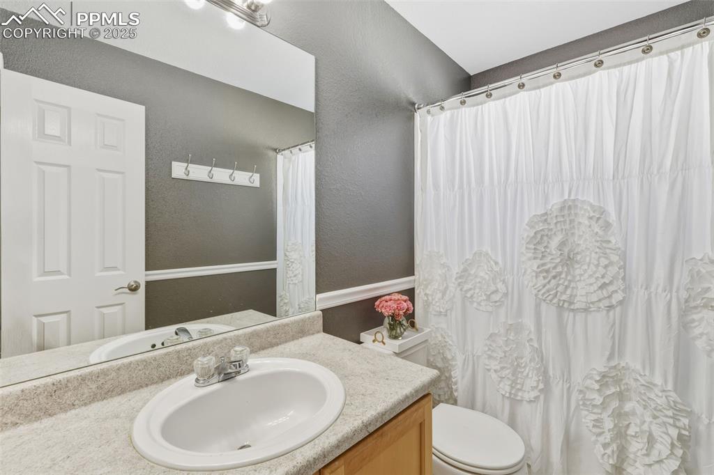 Image 28 of 34: Full bathroom with a textured wall, vanity, and a shower with curtain