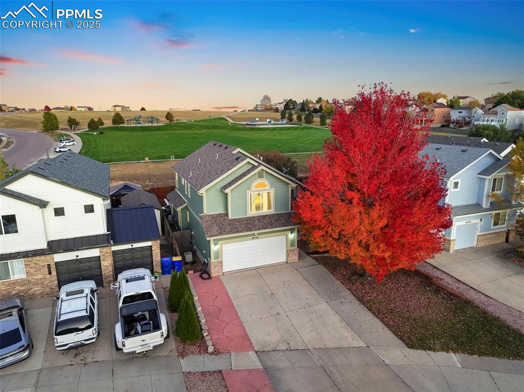 Image 3 of 34: View of front of house with driveway, a garage, a metal roof, stone siding,