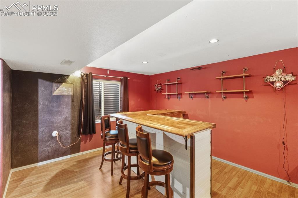 Image 31 of 34: Indoor dry bar featuring light wood-type flooring, wooden counters, recesse