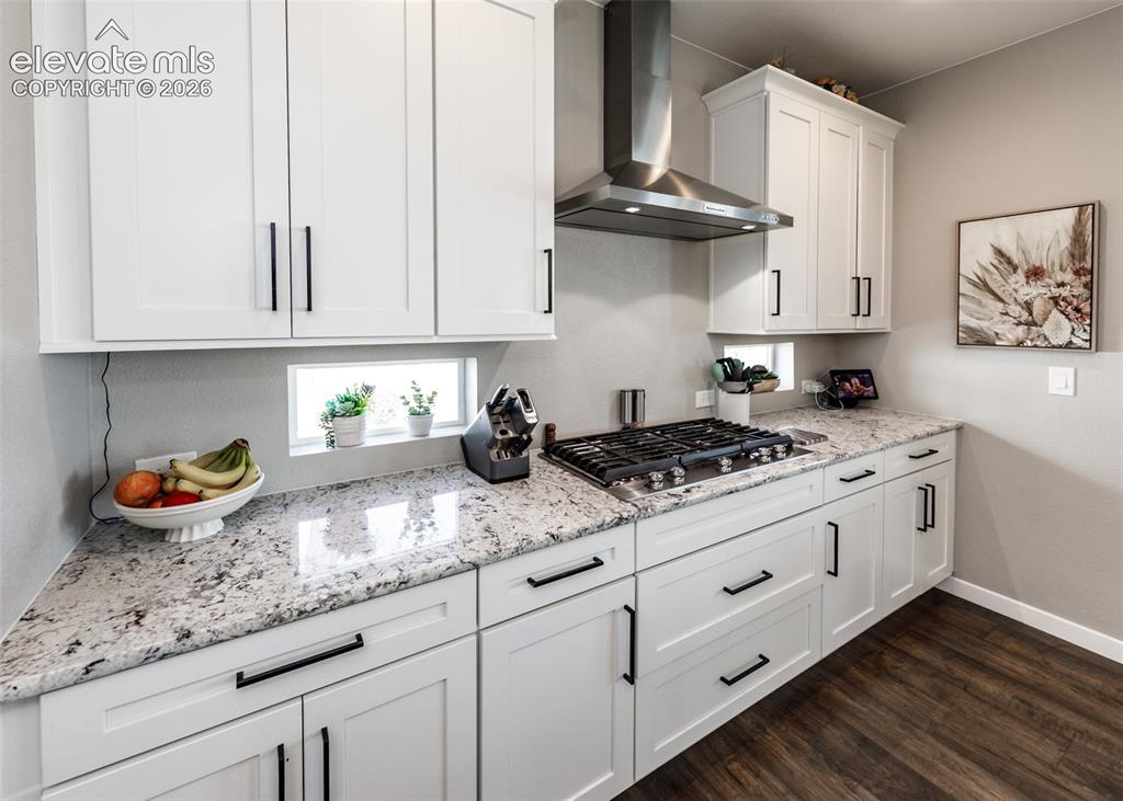 Image 14 of 50: White shaker-style cabinetry with black hardware, stainless steel range hoo