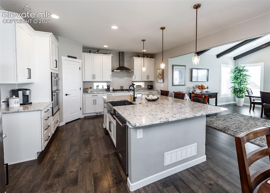 Image 16 of 50: Kitchen featuring wood-finish flooring, white cabinetry, a large center isl