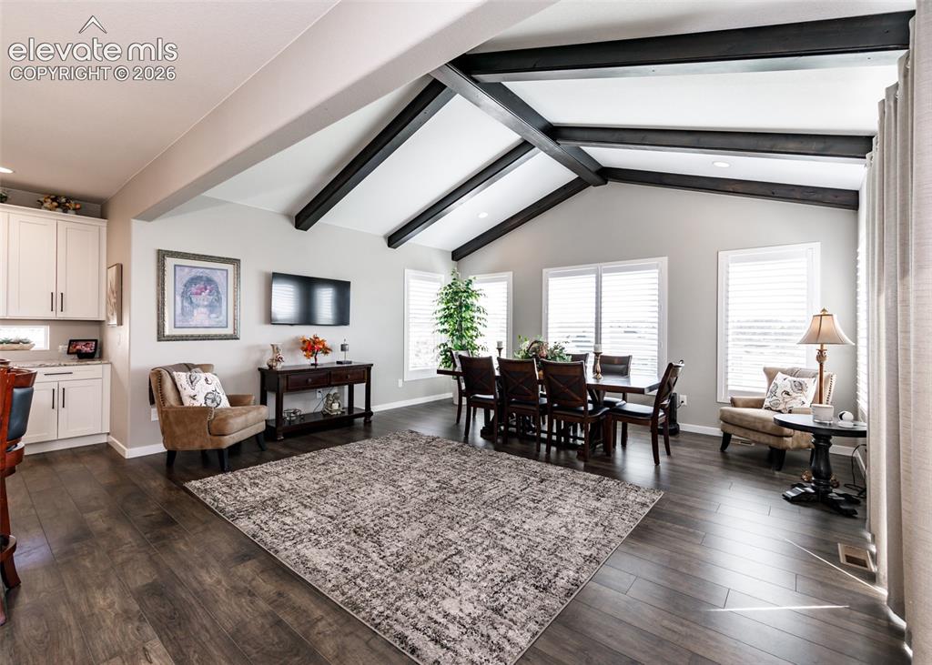 Image 18 of 50: Vaulted ceiling with exposed dark wood beams, wood-finish flooring, white c