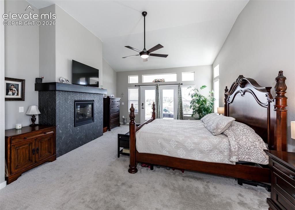 Image 23 of 50: Vaulted ceiling with ceiling fan, tiled fireplace, double French doors, tra