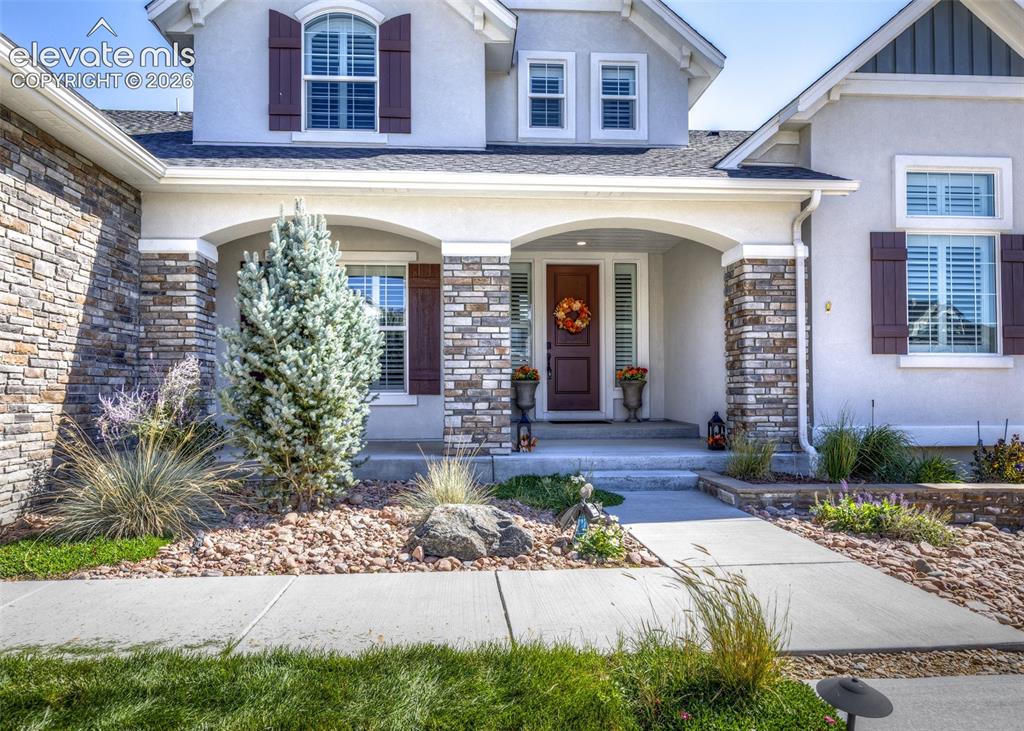 Image 3 of 50: Stucco exterior with stone accents, covered entry, front door with sideligh