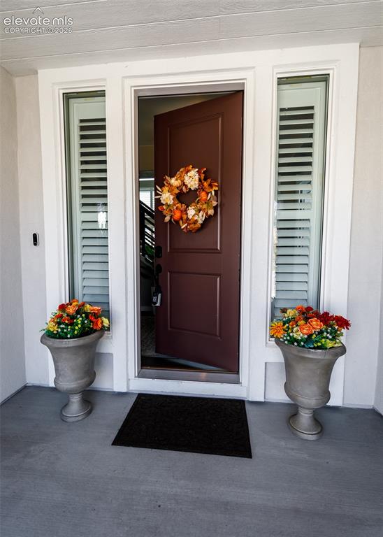 Image 4 of 50: Entry with a solid-panel door, sidelights with plantation shutters, and a c