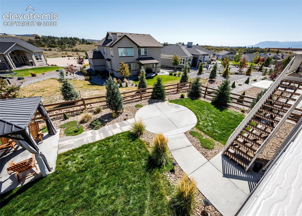 Image 49 of 50: Manicured lawn with a circular concrete patio, concrete pathways, and a woo