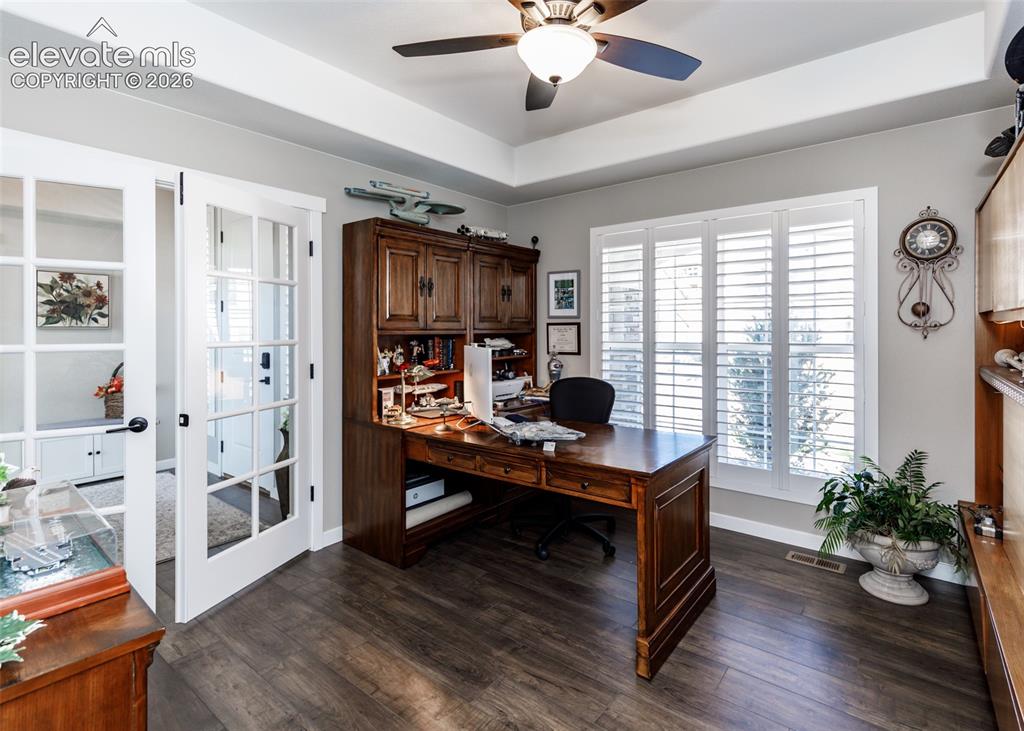 Image 8 of 50: Tray ceiling with a ceiling fan, wood-finish flooring, and white plantation
