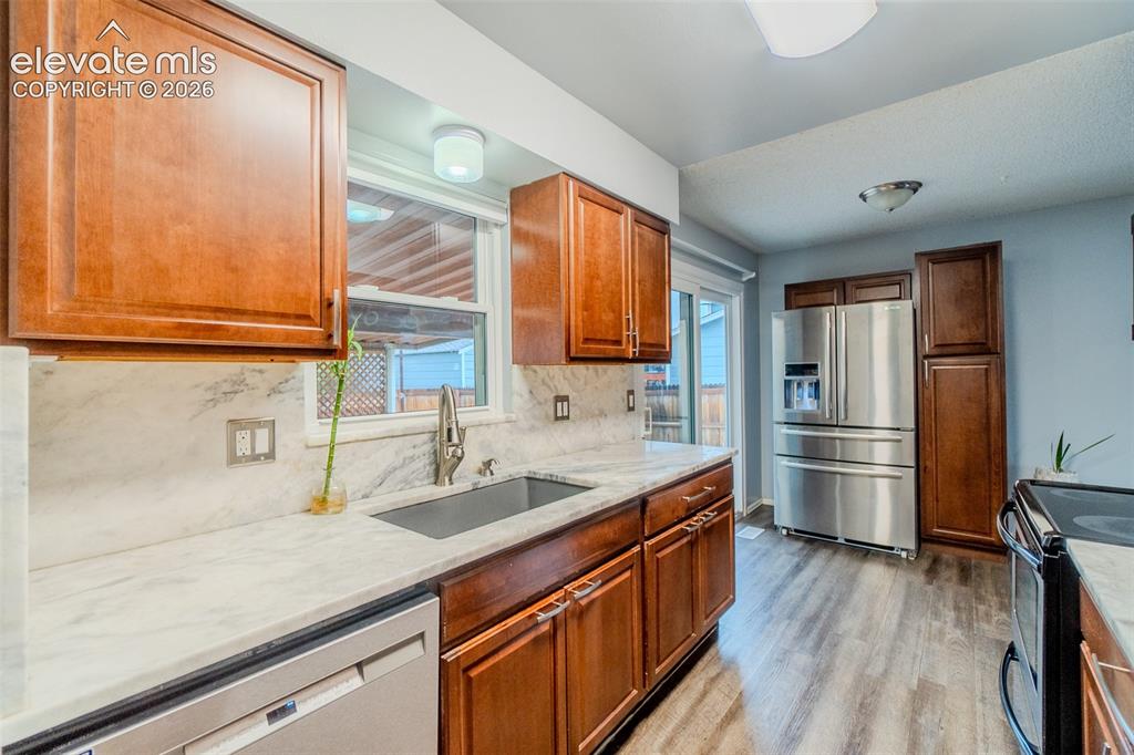 Image 11 of 33: Kitchen featuring wood cabinetry, marble countertops with an farm sink with