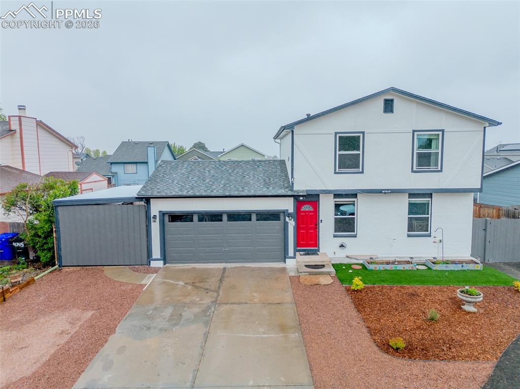 Image 2 of 33: Extra wide driveway with carport, manicured front lawn with bright red door