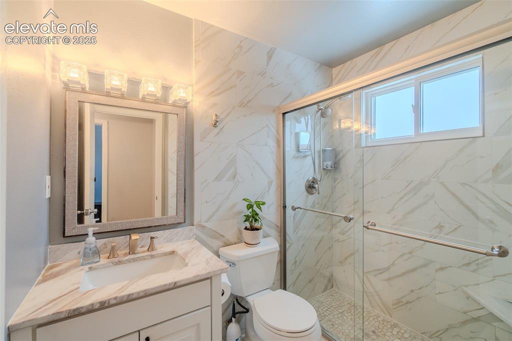 Image 21 of 33: Upstairs Remolded Bathroom featuring a glass-enclosed shower with white mar