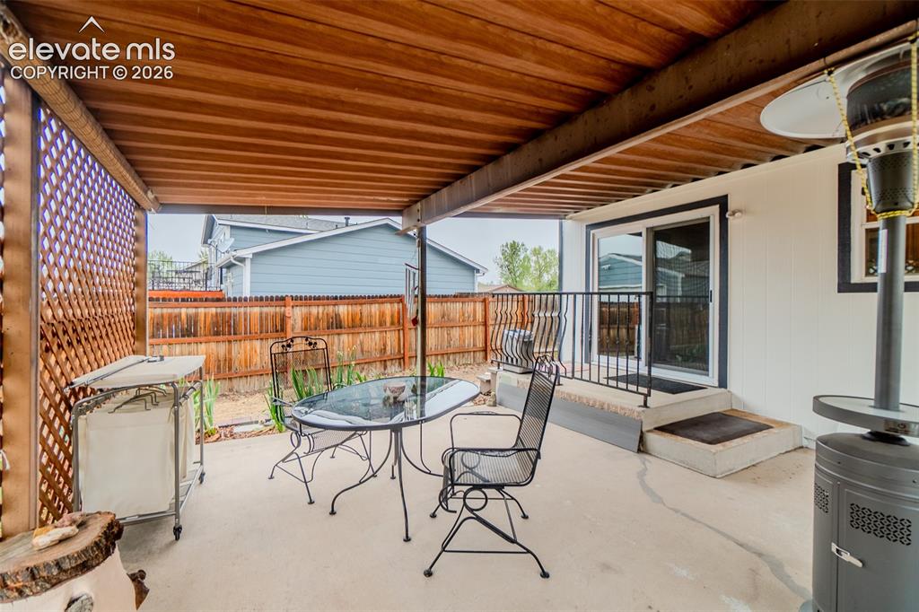 Image 29 of 33: Covered patio featuring a wood-slat ceiling, privacy lattice, concrete floo