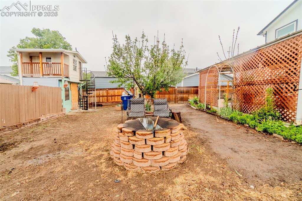 Image 32 of 33: Expansive backyard featuring a brick fire pit, wood fencing, behind the fen