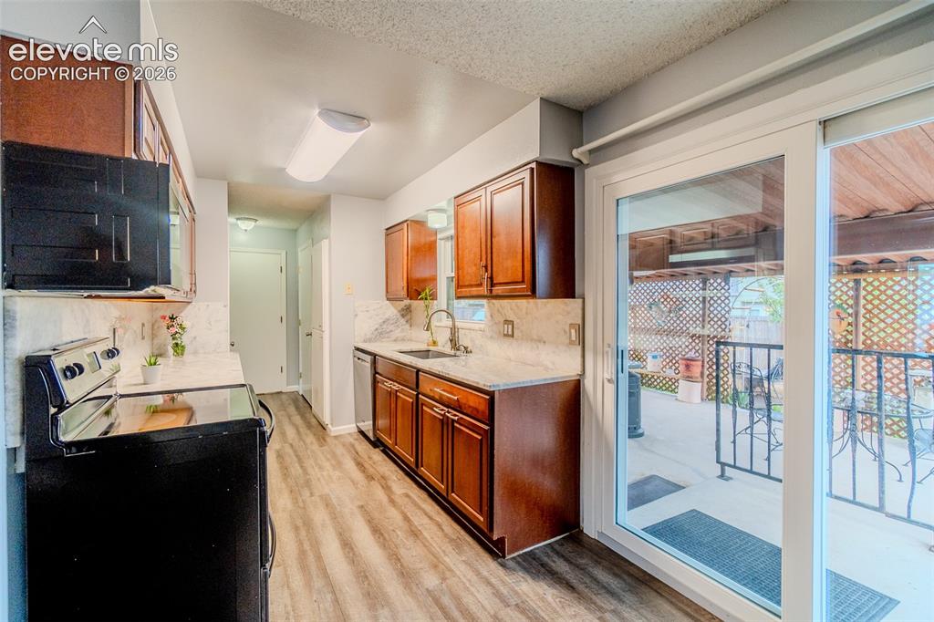 Image 8 of 33: Kitchen featuring wood-finish flooring, wood cabinetry, marble countertops 