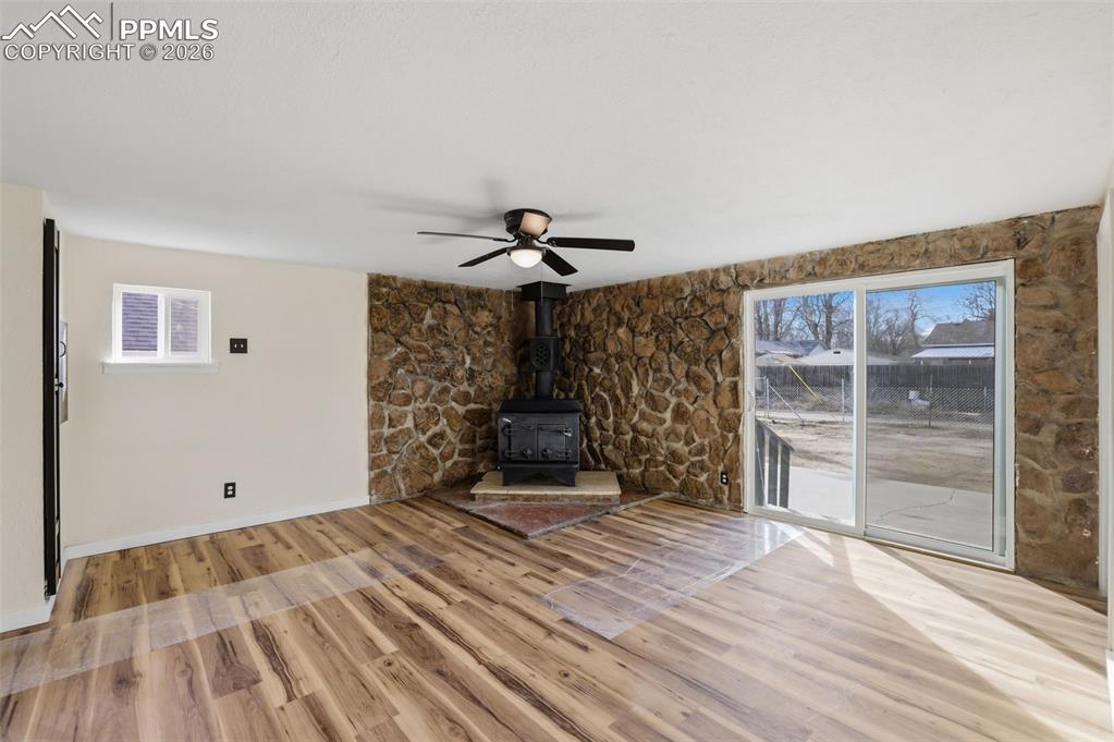 Image 13 of 36: Unfurnished living room with a wood stove, plenty of natural light, light w