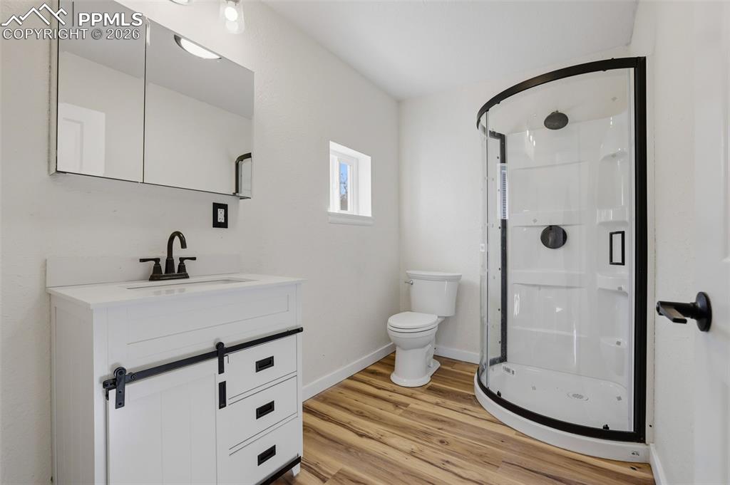Image 15 of 36: Bathroom with vanity, a stall shower, and light wood-style floors