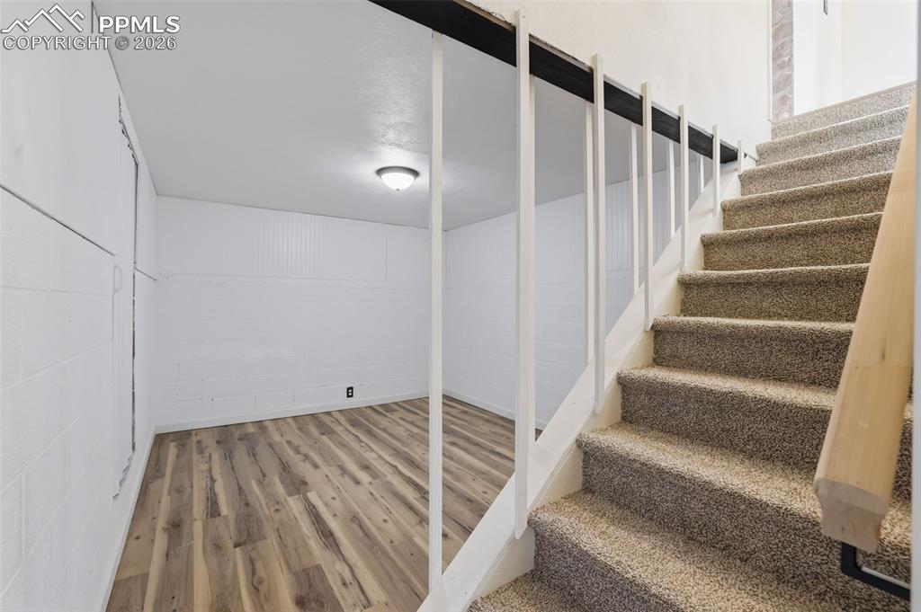 Image 21 of 36: Stairs featuring concrete block wall and wood finished floors