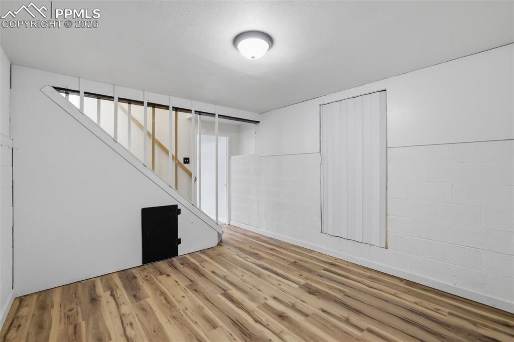 Image 22 of 36: Finished basement featuring concrete block wall and wood finished floors