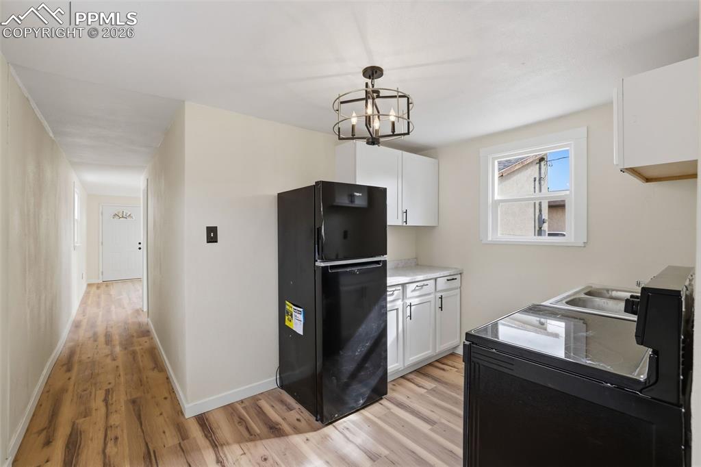 Image 30 of 36: Kitchen featuring freestanding refrigerator, white cabinetry, light counter