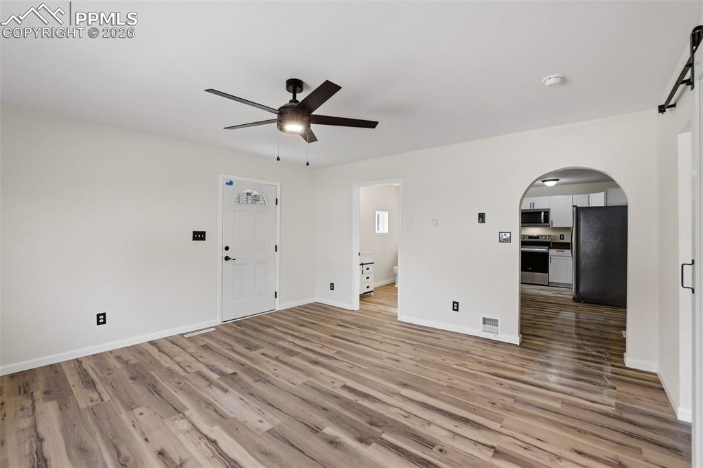 Image 7 of 36: Unfurnished living room featuring arched walkways, a barn door, ceiling fan