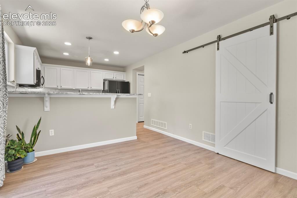 Image 11 of 46: Open-concept room featuring wood-finish flooring, a white barn door, a brea