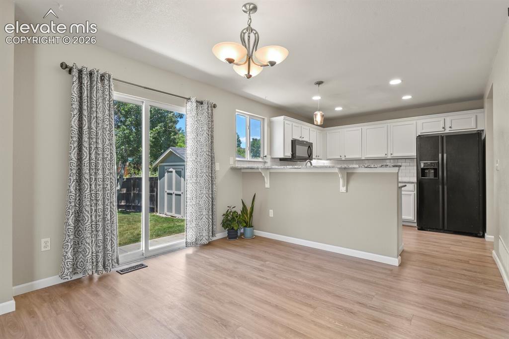 Image 12 of 46: Open-concept area featuring wood-finish flooring, a contemporary chandelier