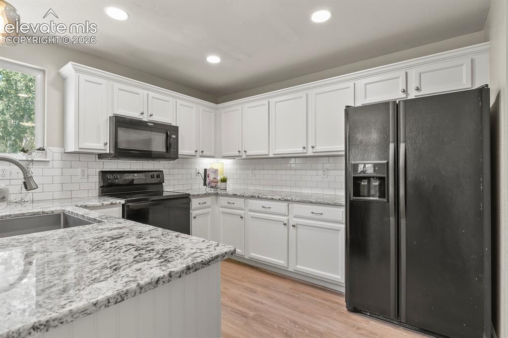 Image 13 of 46: Modern kitchen featuring white cabinetry, granite countertops, subway tile
