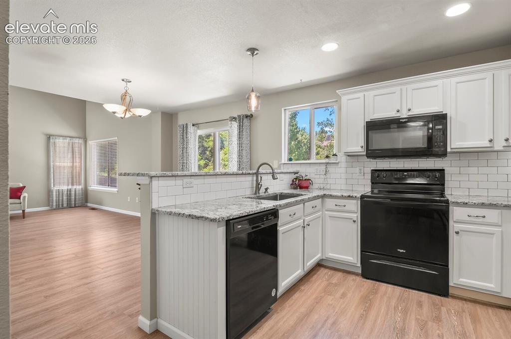 Image 15 of 46: Open-concept kitchen featuring white cabinetry, black appliances, a subway