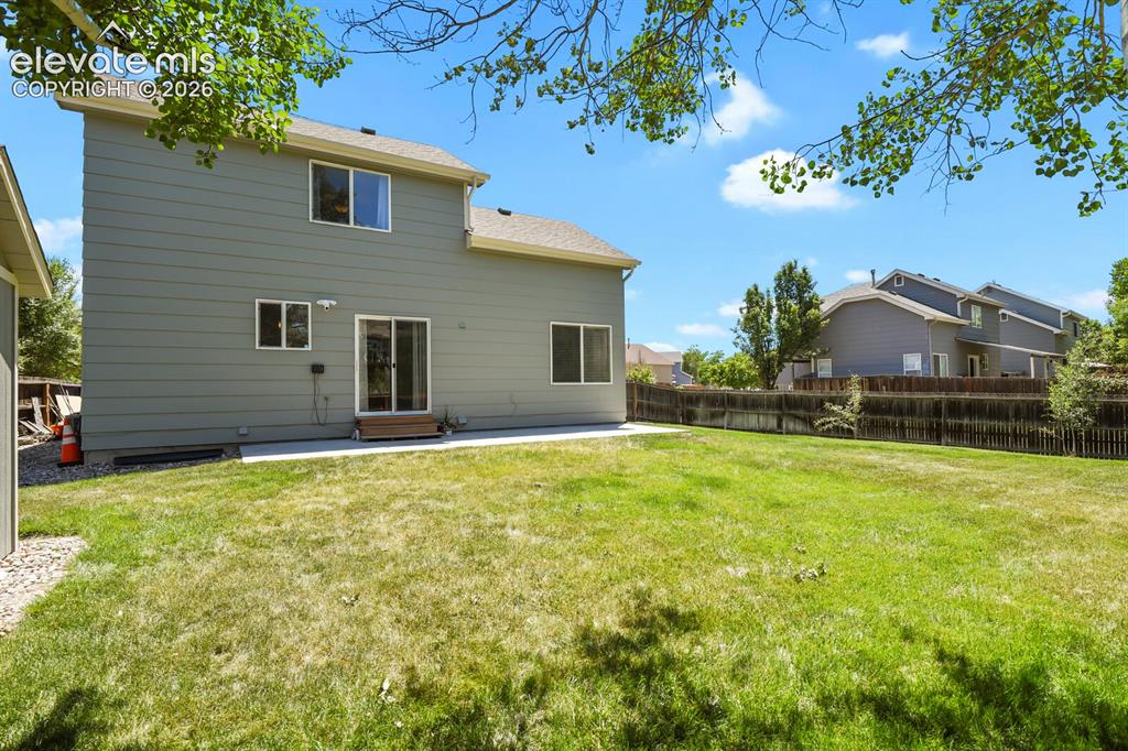 Image 33 of 46: Expansive rear yard featuring a large grass area, wood privacy fence, and c