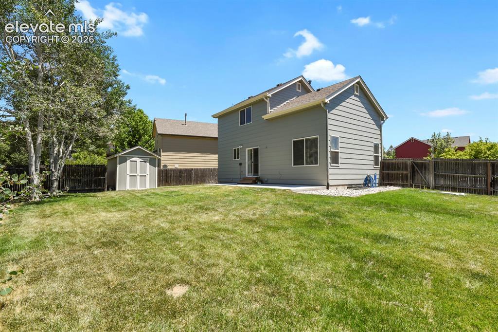 Image 34 of 46: Expansive backyard featuring a large green lawn, perimeter wood fencing, an