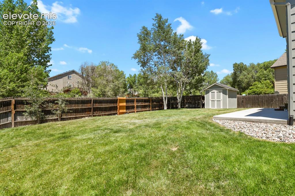 Image 35 of 46: Expansive fenced backyard featuring a manicured lawn, a concrete patio, and