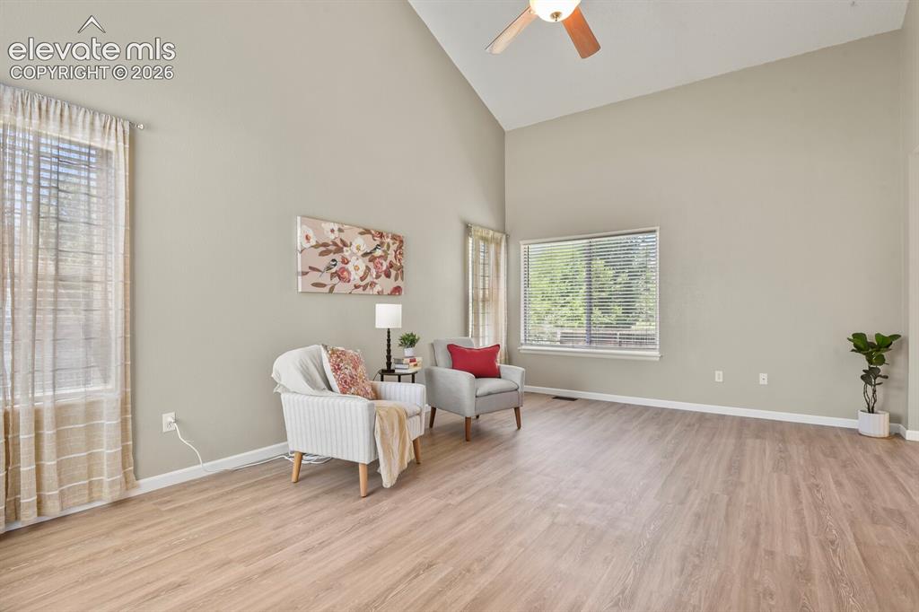 Image 6 of 46: Living area featuring vaulted ceilings, wood-finish flooring, and multiple