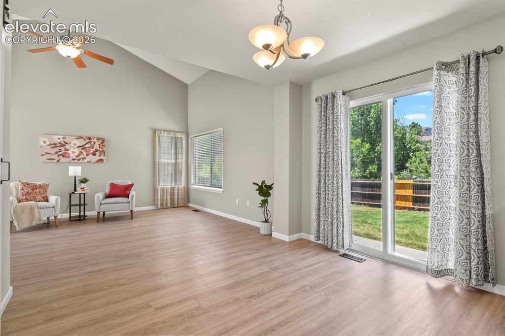 Image 9 of 46: Spacious common area featuring vaulted ceilings, wood-finish flooring, and