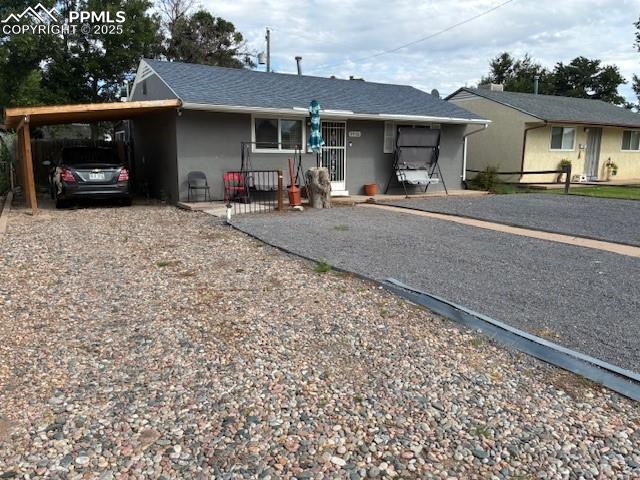 Caption: Single story home with a carport, driveway, and stucco siding