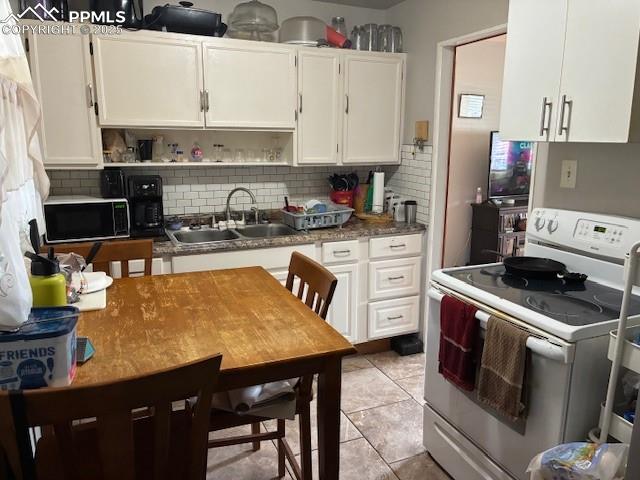 Image 4 of 12: Kitchen with electric range, backsplash, white cabinets, open shelves, and 