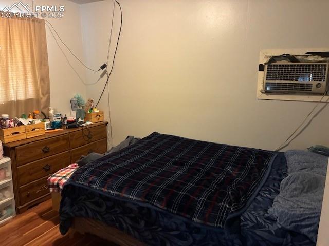 Image 7 of 12: Bedroom featuring wood finished floors and a wall mounted AC