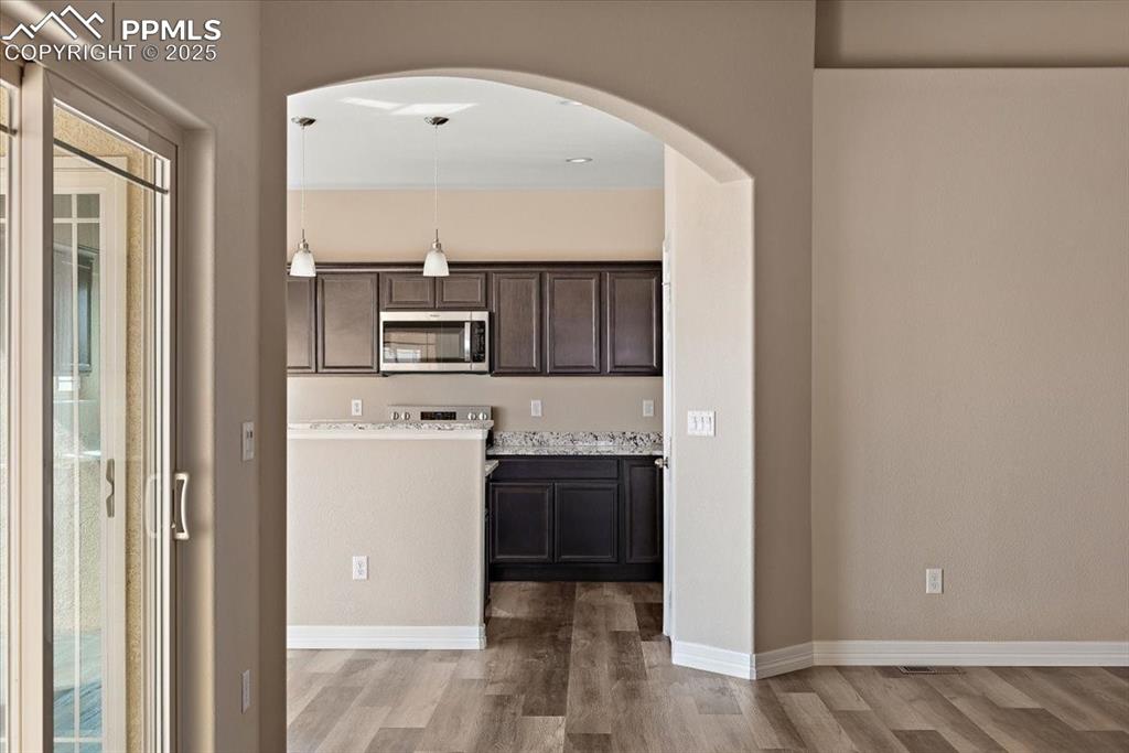 Image 10 of 45: Kitchen featuring baseboards, stainless steel microwave, wood finished floo