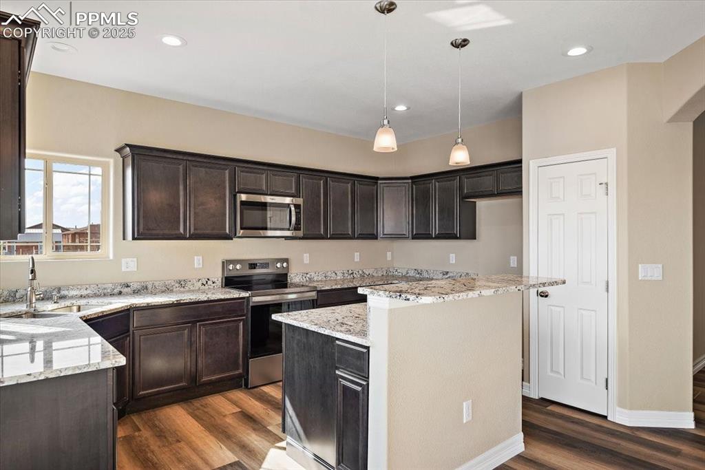 Image 15 of 45: Kitchen featuring light stone counters, a kitchen island, a sink, appliance