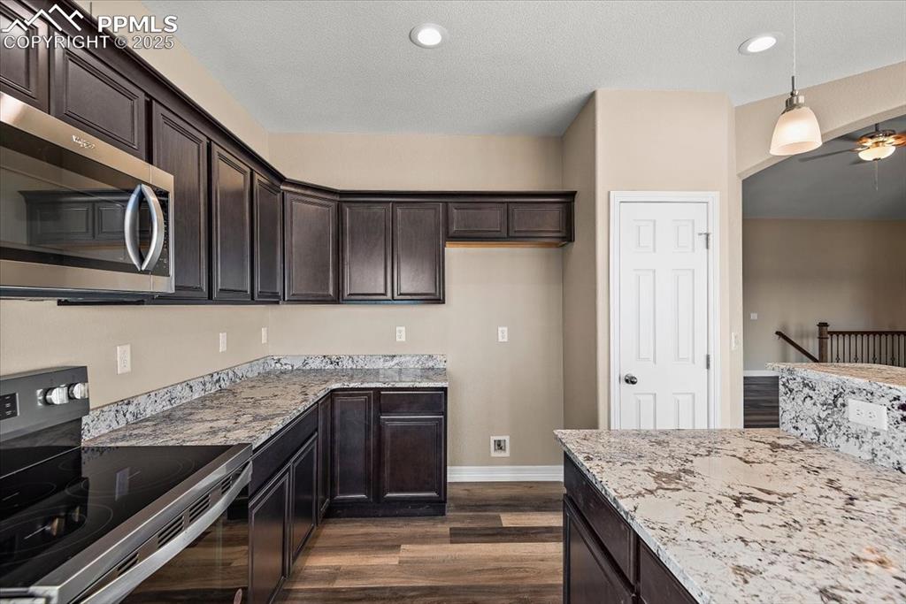 Image 16 of 45: Kitchen with dark wood-style floors, stainless steel microwave, hanging lig