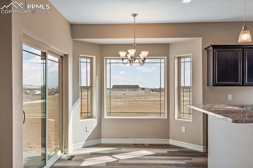 Image 18 of 45: Unfurnished dining area featuring baseboards, a chandelier, and wood finish