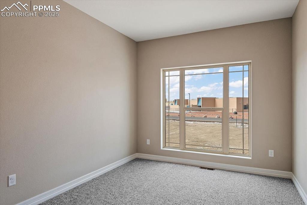 Image 21 of 45: Empty room featuring a view of city, carpet flooring, visible vents, and ba
