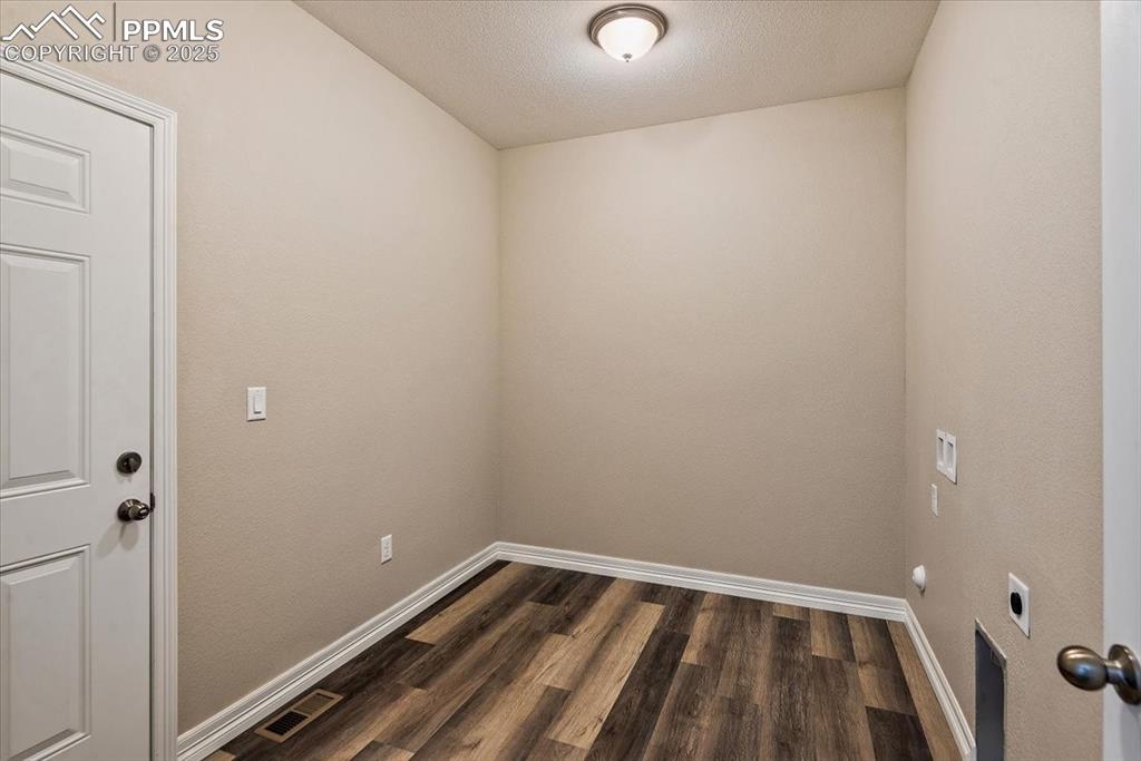 Image 24 of 45: Laundry area with dark wood finished floors, visible vents, hookup for an e